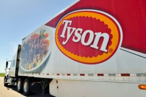 A tyson truck with large logo drives down the highway.