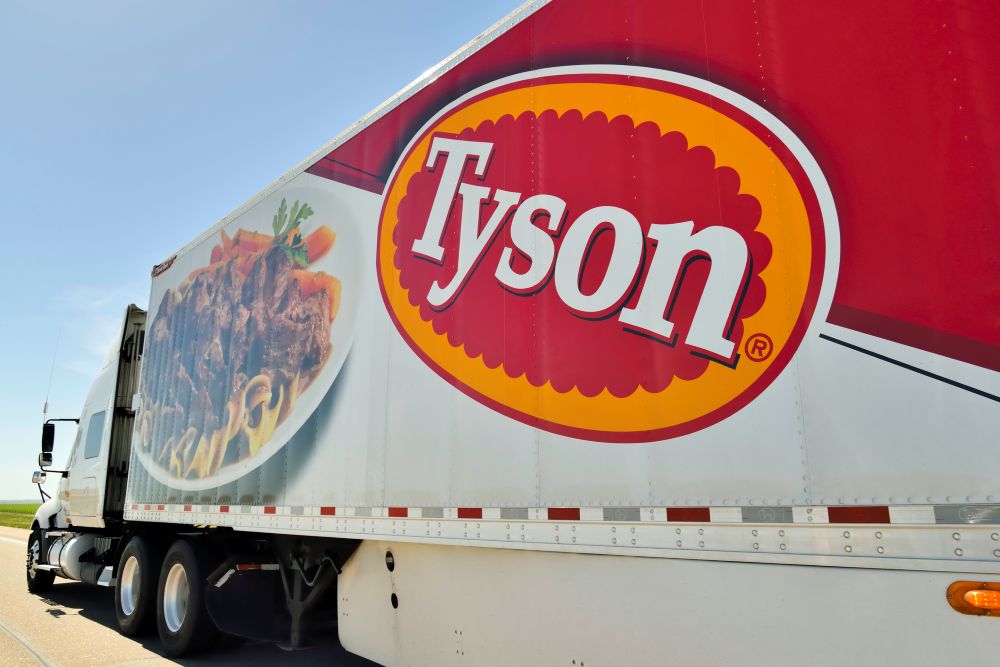 A tyson truck with large logo drives down the highway.