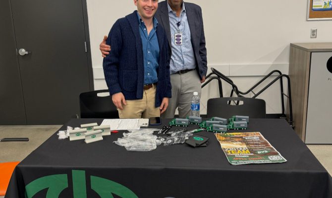 Abbas Alodan and a representative from Owen stand in front of a table at a Refugee Career Fair held at Lutheran Family Services.