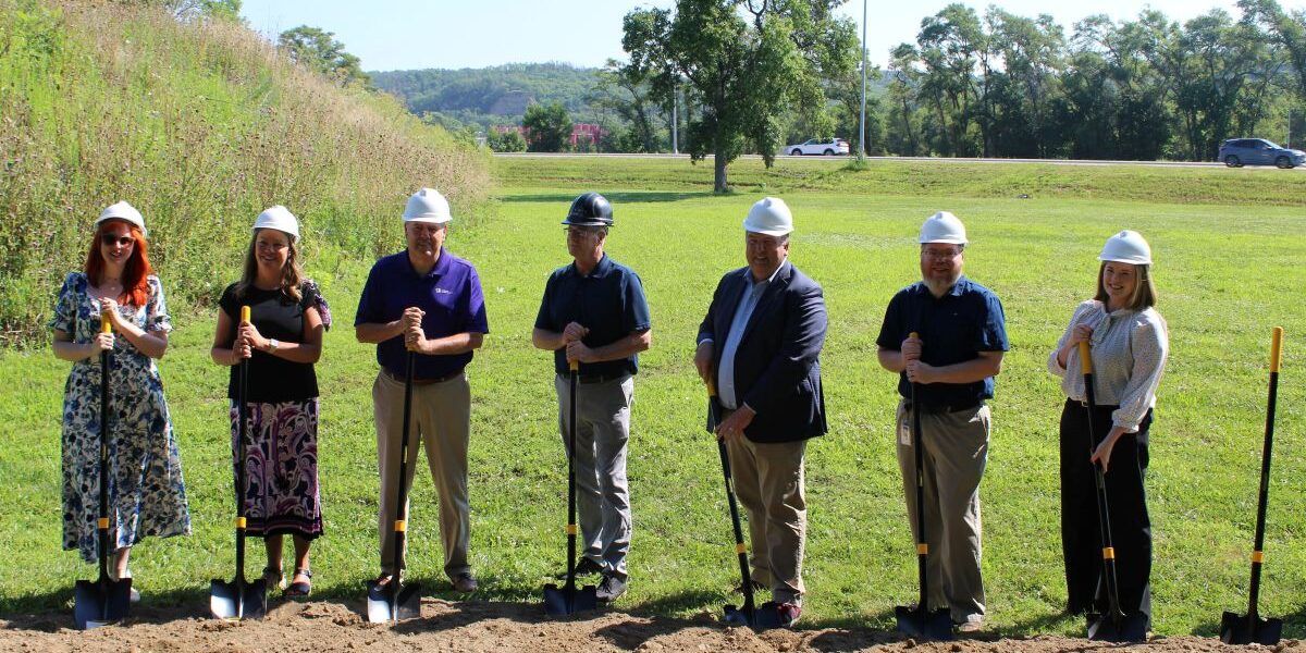 Several LFS team members stand in a field with shovels to break ground on the development of Spin Lofts.