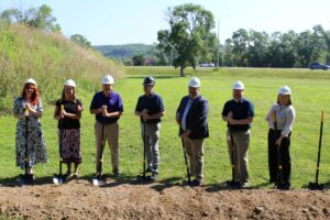 Several LFS team members stand in a field with shovels to break ground on the development of Spin Lofts.