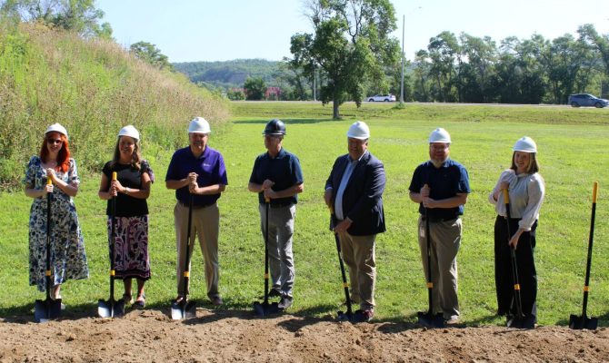 Several LFS team members stand in a field with shovels to break ground on the development of Spin Lofts.