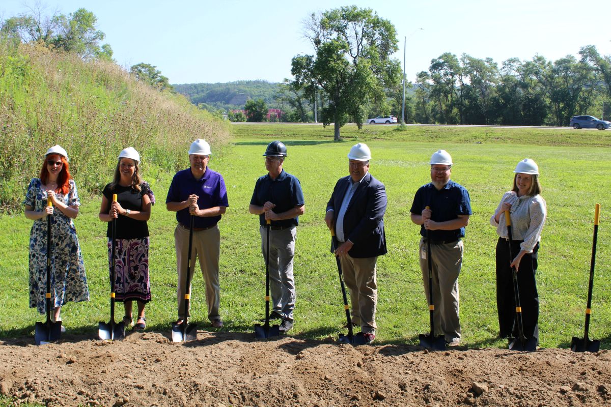 Several LFS team members stand in a field with shovels to break ground on the development of Spin Lofts.
