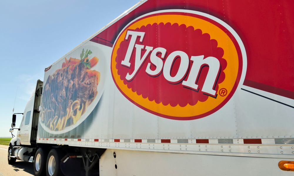 A Tyson truck with large logo drives down the highway.