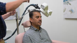 A client sits to receive TMS treatment for depression