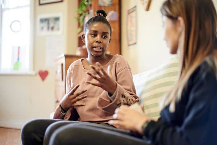 Children's Mental Health sized A girl speaks to a therapist while sitting on a couch.