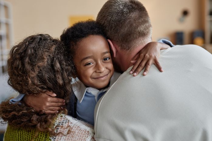 Children's Services LFS A child smiles and embraces his mom and dad.
