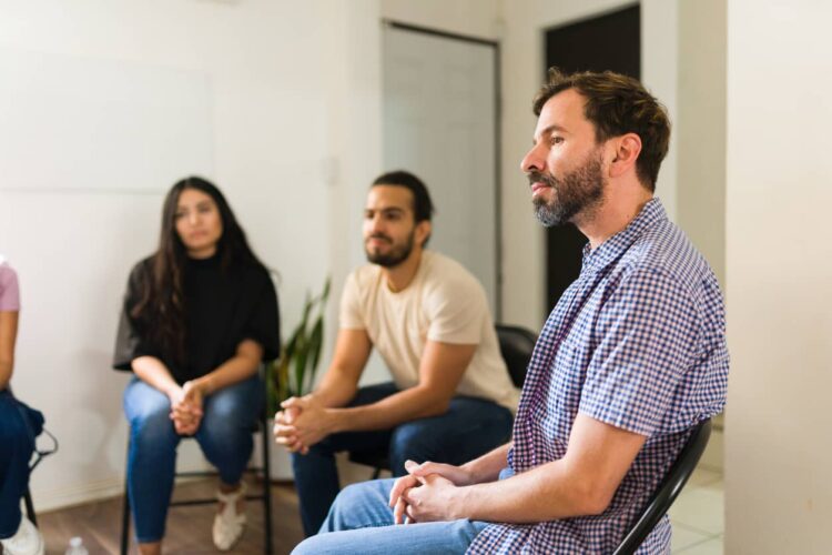 People sit around in a circle at an Intensive Outpatient program and discuss recovery.