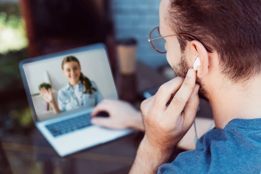 Telehealth client A man sits at a computer and speaks to a therapist on screen.